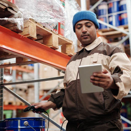 A man holding a tablet in a warehouse.