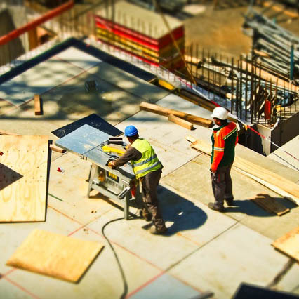 Two construction workers are working on a building.