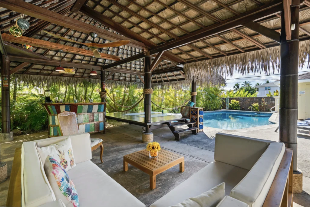 A living room with a couch and chairs near the pool