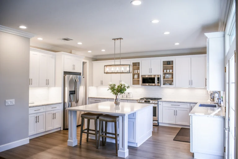 A kitchen with white cabinets and wooden floors.