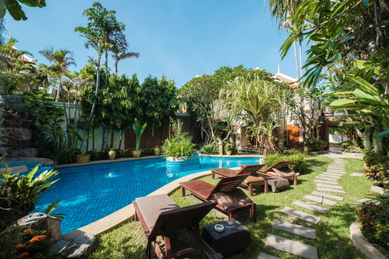 A pool with chairs and trees in the background